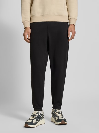 Männermodel trägt Regular Fit Sweatpants aus Baumwoll-Mix von Tommy Jeans, Optik: Unifarben, Materialverarbeitung: Sweat, Ganzkörperansicht von vorne.