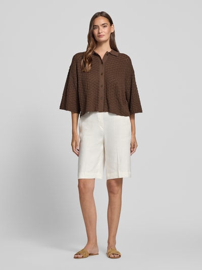 Vrouwenmodel draagt gebreid shirt van puur katoen met boxy fit, polokraag, knoopsluiting, 3/4-mouw model 'LOYSIA' van DRYKORN, ruglengte maat S 50 cm, mouwlengte 34 cm. Ganzlichaamsaanzicht van voren.