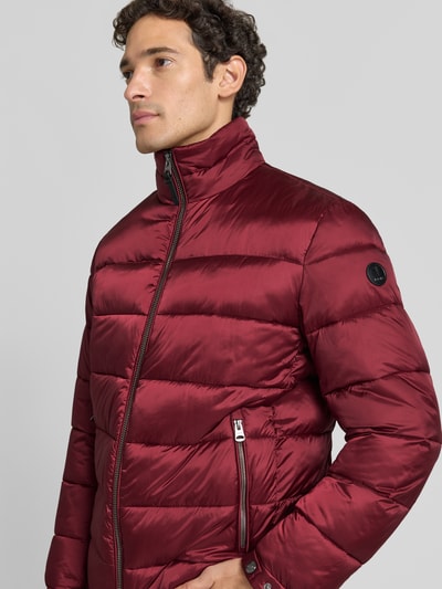 Männermodel trägt Regular Fit Steppjacke mit Stehkragen von JOOP! in dunklem Rot, glänzende glatte Oberfläche, Nahaufnahme Oberkörper, Herren Bomberjacke / Blouson von JOOP! COLLECTION.