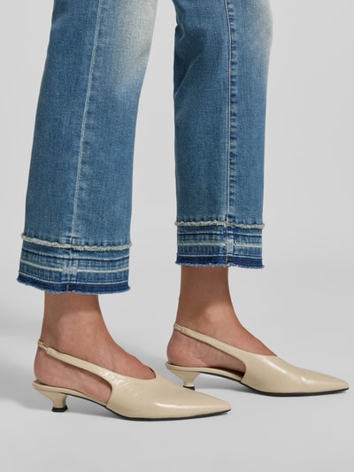 Frauenmodel trägt Flared Fit Jeans aus Baumwoll-Mix in verkürzter Passform von Marc Cain, mittlerer Blauton, helle Waschung, 5-Pocket-Design, sichtbare Nahtdetails, Damen Jeans, Nahaufnahme Beinausschnitt.