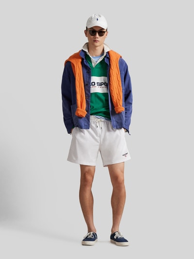 Männermodel trägt weiße Badeshorts mit Label Stitching von Polo Ralph Lauren, unifarben mit Tunnelzug und Taschen, Ganzkörperansicht von vorne.