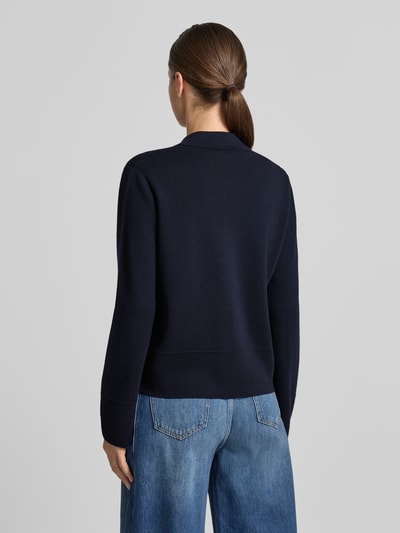 Frauenmodel trägt Strickjacke aus reiner Schurwolle Modell 'SNACK' von MM by Max Mara in Dunkelblau, glatte Textur, Ganzkörperansicht Rückansicht.