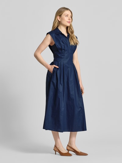 Frauenmodel trägt Midikleid mit verdeckter Knopfleiste Modell 'CHERRY' von Guess aus reiner Baumwolle, taillierter Schnitt, navyblau, Kappärmel, Hemdblusenkragen, Ganzkörperansicht von vorne.
