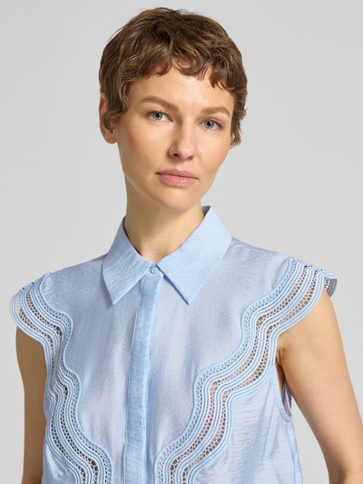 Frauenmodel trägt Blusentop mit Lochstickerei Modell 'COLE' von Copenhagen Muse, hellblauer Modal-Mix, sichtbare Struktur, Nahaufnahme Oberkörper.