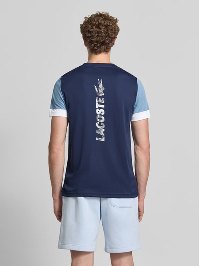 Männermodel trägt Regular Fit Sport-T-Shirt im Colorblock-Design von Lacoste Sport in Dunkelblau und Hellblau, Ganzkörperansicht Rückansicht.