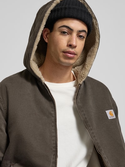 Männermodel trägt Jacke mit Zweiwege-Reißverschluss Modell 'MITCH' von Carhartt Work In Progress in Braun, Baumwolle, Label-Detail, Nahaufnahme Oberkörper.