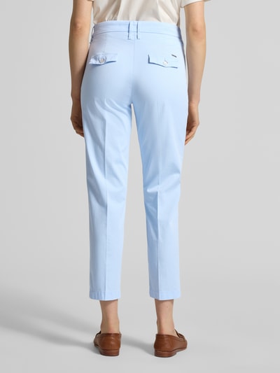 Frauenmodel trägt hellblaue Hose in verkürzter Passform Modell 'Mara S' von Brax aus Baumwoll-Lyocell-Mix mit Bügelfalten und Eingrifftaschen, Ganzkörperansicht Rückansicht.