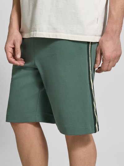 Männermodel trägt grüne Shorts mit elastischem Bund von EA7 Emporio Armani, Baumwoll-Mix, Regular Fit, Nahaufnahme Oberkörper.
