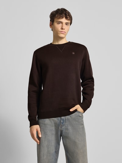 Männermodel draagt Sweatshirt aus Baumwoll-Mix Modell 'Premium core' van G-star in recht pasvorm, ronde hals, labelstitching, elastische boorden, kleur donkerbruin, katoenmengsel, ruglengte bij maat M 66 cm, mouwlengte 67 cm, Ganzkörperansicht van voren.