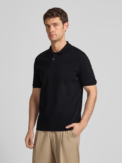 Männermodel trägt Poloshirt aus Baumwolle von MARC O’POLO DENIM in Schwarz, Piqué-Struktur, gerader Schnitt, Nahaufnahme Oberkörper.