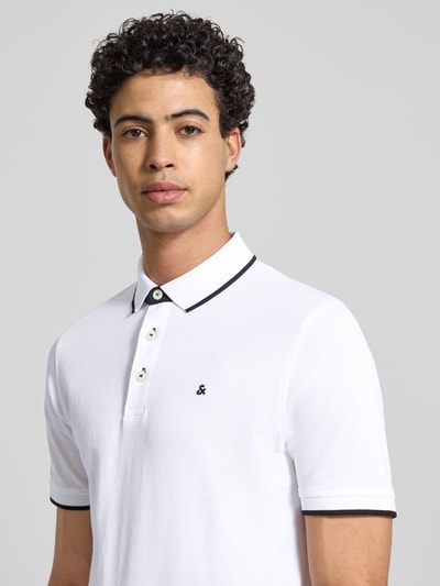 Männermodel trägt Slim Fit Poloshirt mit Viskose-Anteil Modell 'Paulos' von JACK & JONES, Baumwoll-Mix, Kurzärmelig, Logo-Stitching, Nahaufnahme Oberkörper.