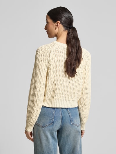 Frauenmodel trägt Strickjacke mit Rundhalsausschnitt von Oui aus Baumwoll-Mix in Regular-Fit, cremefarben, Strukturstrick, Rückenlänge 44 cm, Ärmellänge 77 cm, Knopfleiste, Ganzkörperansicht Rückansicht.