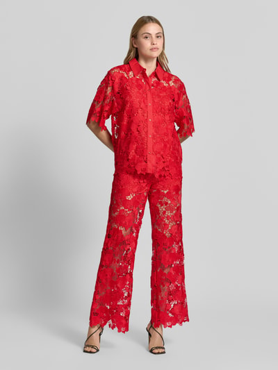 Frauenmodel trägt Regular Fit Bluse aus Spitze Modell 'GALA' von YAS in leuchtendem Rot, Knopfleiste, Hemdblusenkragen, transparente florale Struktur, Damen Bluse mit kurzen Ärmeln, Ganzkörperansicht von vorne.