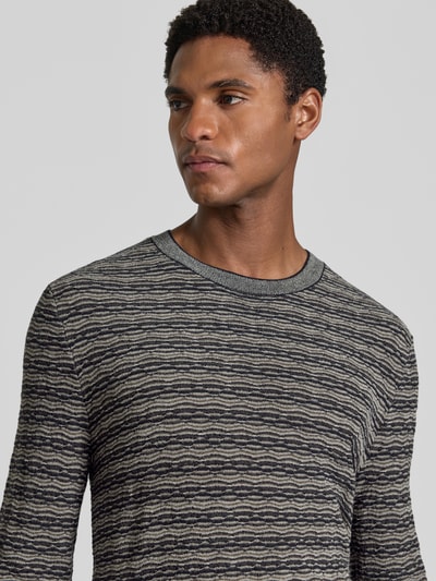 Männermodel trägt Strickpullover mit Lanawolle von Emporio Armani, grau gemustert, Rundhalsausschnitt, Nahaufnahme Oberkörper.