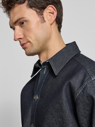 Männermodel trägt Oversized Jeansjacke aus reiner Baumwolle Modell 'EMIKOL' von HUGO in Dunkelblau, Optik: Unifarben, Denim, Nahaufnahme Oberkörper.