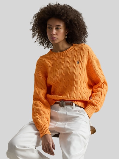 Vrouwenmodel draagt Regular Fit Strickpullover aus reiner Baumwolle van Polo Ralph Lauren, oranje, kabelpatroon, logo, lange mouw, katoen, unifarben, crew neck, geribde manchetten en zoom, detailopname bovenlichaam.