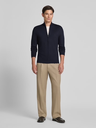 Männermodel trägt Slim Fit Strickjacke aus Viskose-Mix mit Stehkragen von MCNEAL in Dunkelblau, beiger Hose, Ganzkörperansicht von vorne.
