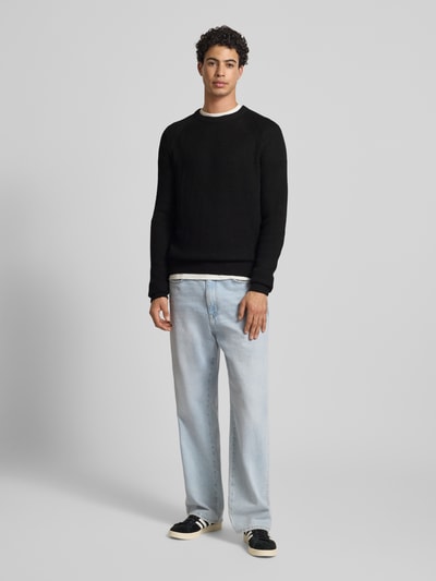 Męski model nosi Strickpullover mit Rundhalsausschnitt Modell 'PANNEL' od Jack & Jones, materiał z bawełną, krój slim fit, czarny, cały przód.