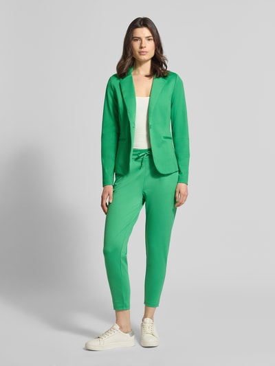 Frauenmodel trägt Regular Fit Blazer mit Viskose-Anteil Modell 'Kate' von ICHI in Grün, Elastischer-Material-Mix, Reverskragen, Paspeltaschen, Knopfverschluss, Tailliert, Ganzkörperansicht von vorne.