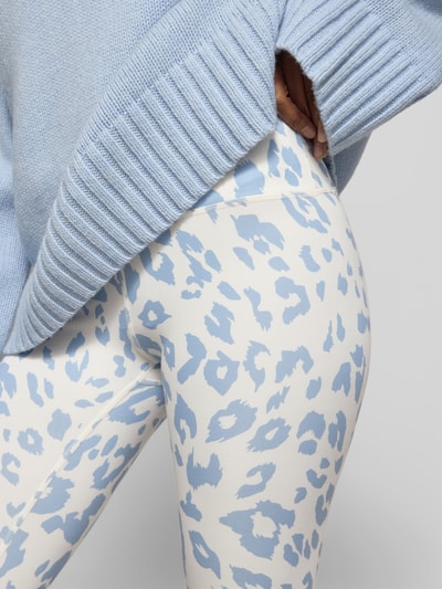 Frauenmodel trägt Leggins mit Allover-Animal-Print von Juvia in Blau und Weiß, Slim-Fit, breiter Bund, Knöchellänge, Nahaufnahme Oberkörper.