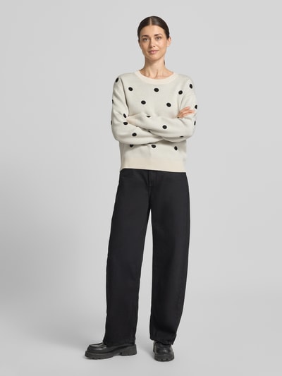 Frauenmodel trägt Strickpullover aus Viskose-Mix Modell 'Flow' von FREE/QUENT, cremefarben mit schwarzen Punkten, Ganzkörperansicht von vorne.