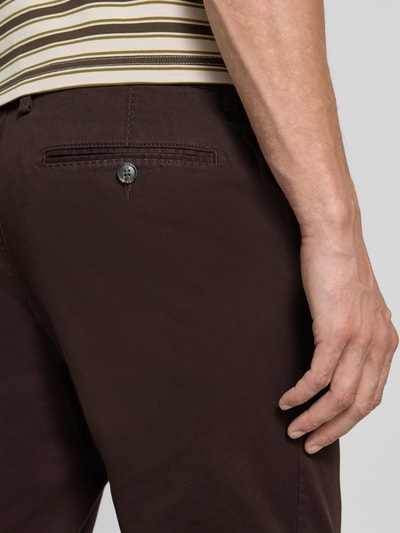 Mężczyzna nosi Hose mit Gesäßtaschen von Christian Berg Men z mieszanki bawełny i elastanu, krój slim fit, wpuszczane kieszenie, kieszenie z tyłu, kolor ciemnobrązowy, szerokość w rozmiarze 50: 45 cm, długość wewnętrzna nogawki w rozmiarze 50: 80 cm, detailaufnahme tyłu.