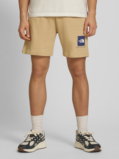Mężczyznamodel nosi Regular Fit Shorts mit Eingrifftaschen von The North Face, mieszanka bawełny, beżowy kolor, szerokość w rozmiarze M 40 cm, długość wewnętrzna nogawki w rozmiarze M 18 cm, wpuszczane kieszenie i kieszeń z tyłu, widok całej sylwetki z przodu.