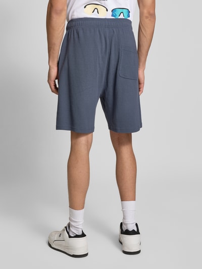 Männermodel trägt Shorts mit Logo-Print und Eingrifftaschen von ANOTHER COTTON LAB, Blau, Baumwoll-Mix, Lockerer-Schnitt, Ganzkörperansicht Rückansicht.