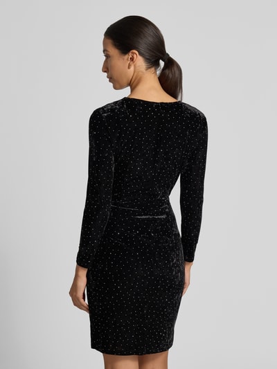 Vrouwenmodel draagt Samtkleid in Minilänge mit Stretch-Anteil van Apricot, zwart fluweel, getailleerde pasvorm, strassteentjes, rugaanzicht.