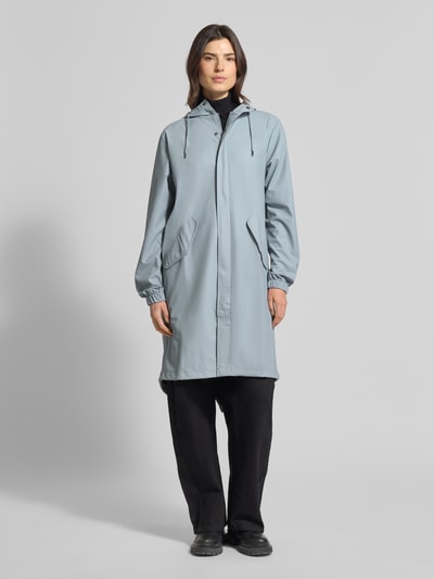 Frauenmodel trägt Regular Fit Parker mit Kapuze Modell 'Fishtail' von Rains in Hellgrau, Pattentaschen, elastische Ärmelabschlüsse, glatte Texture, Ganzkörperansicht von vorne, Rückenlänge bei Größe S: 104 cm, Schulterbreite: 45 cm, Brustweite: 55 cm, Ärmellänge: 65 cm.