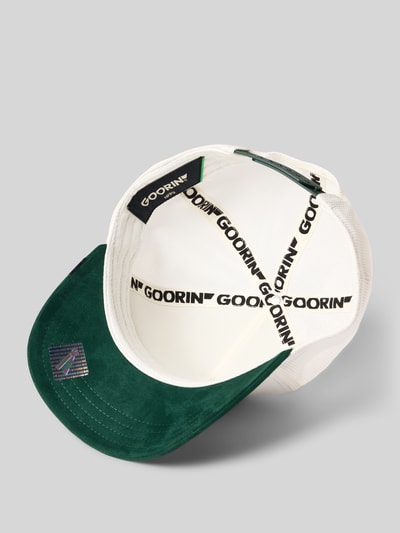 Produktfoto, grüne und weiße Trucker Cap mit Motiv-Patch Modell 'Suede Duck' von GOORIN BROS., Material-Mix mit Baumwoll-Anteil, verstärkter Schirm, Größenverstellbar, Innenansicht mit schwarzen Logo-Details, texturierte Oberflächen.