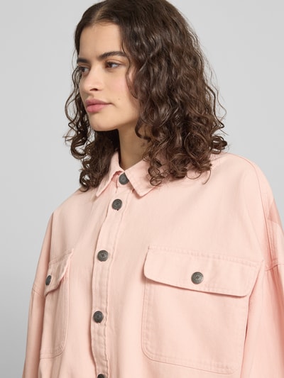 Frauenmodel trägt Oversized Hemdjacke mit Brusttaschen von Karo Kauer aus reiner Baumwolle in Rosa, Umlegekragen, Knopfleiste, Nahaufnahme Oberkörper.