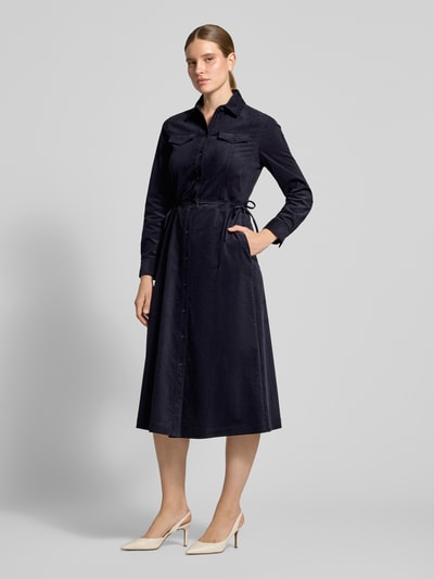 Vrouwenmodel draagt Regular Fit midi-jurk uit katoenmix in corduroy look van Marc Cain, donkerblauw, platte kraag, borstzakken, knoopsluiting, geheel lichaam van voren. Ruglengte maat 36: 128 cm, borstwijdte: 51 cm, mouwlengte: 63 cm.