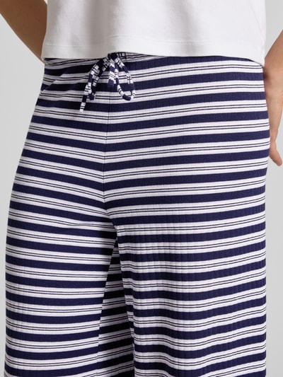 Vrouwenmodel draagt Hose im Allover-Look mit Tunnelzug van Gina Tricot, materiaalmix met viscose, wide leg, elastische band, tunnelkoord, all-over look, bandwijdte maat S 40 cm, binnenbeenlengte 72 cm, marine met witte strepen, detailopname taille.