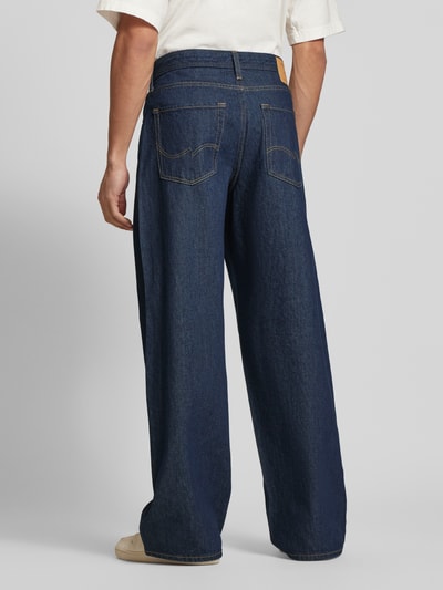 Männermodel trägt Wide Fit Jeans im 5-Pockets-Design Modell 'Dave' von Jack & Jones, dunkelblaue Baumwolle, Ganzkörperansicht Rückansicht.