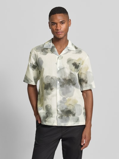 Męski model nosi Regular Fit Freizeithemd mit floralem Allover-Print od JAKE*S STUDIO MEN, bawełniany miks, krój regular fit, pastelowe barwy, strukturalny wzór, kołnierz rewersowy, krótki rękaw, pełny guzik, długość pleców w rozmiarze M: 72 cm, szerokość w rozmiarze M: 45 cm, długość rękawa w rozmiarze M: 30 cm. Ganzkörperansicht von vorne.