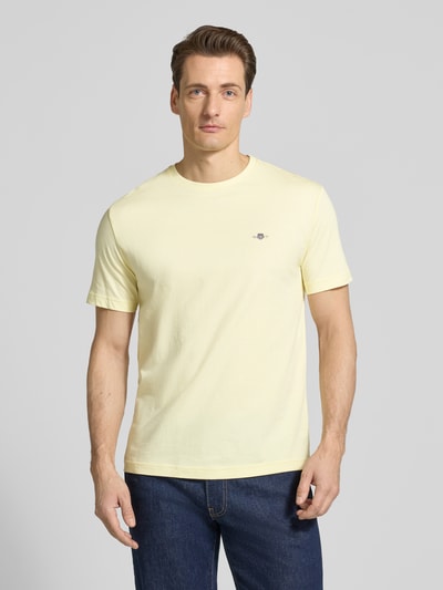 Männermodel trägt Regular Fit T-Shirt mit Logo-Stitching von Gant in Gelb, reine Baumwolle, Rundhalsausschnitt, Ganzkörperansicht von vorne.
