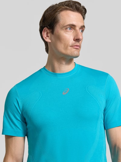 Männermodel trägt Slim Fit RUNNING T-Shirt Modell 'ROAD' von ASICS in Türkis mit Rundhalsausschnitt und metallic Label-Print, Nahaufnahme Oberkörper.