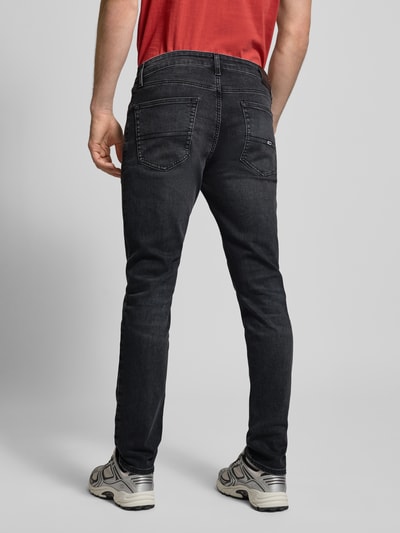 Männermodel trägt Slim Fit Jeans aus Baumwoll-Mix Modell 'AUSTIN' von Tommy Jeans in dunkler Denim-Optik mit Label Patch und 5-Pocket-Design, Ganzkörperansicht Rückansicht.