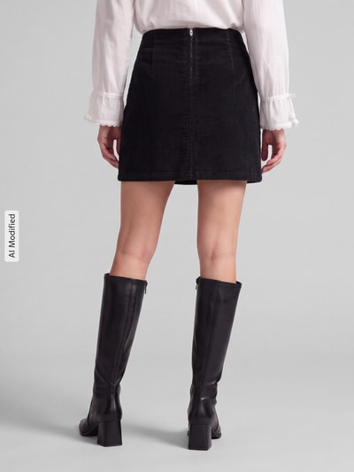 Vrouwenmodel draagt zwarte rok van katoenmix model 'LULA' van VERO MODA met ribtextuur, Dames minirok, volledig zicht van achteren, KI-modificeerd beeld.