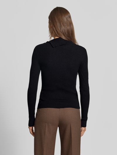 Frauenmodel trägt schwarzen Slim Fit Pullover aus Viskose-Mix in Strick-Optik von MYON, braune Hose, Ganzkörperansicht Rückansicht.