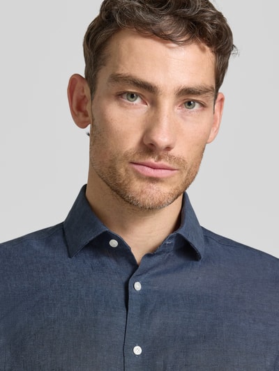 Männermodel trägt Regular Fit Leinenhemd mit Kentkragen von Christian Berg Men in Dunkelblau, reine Leinenstruktur, Nahaufnahme Oberkörper.