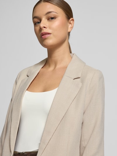 Kobiece modelka nosi Slim Fit Longblazer mit Viskose-Anteil Modell 'FRIDA' od Vero Moda, melange, kremowa, tkanina, krój slim fit, z patkami, bez zapięcia, label stitching, 3/4 rękawy, widok z przodu, zbliżenie na górną część ciała.