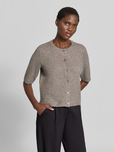 Modelka nosi Regular Fit Cardigan in Strick-Optik Model 'Iga' od VILA, elastyczna mieszanka materiałów, krój regular fit, imitacja dzianiny, Rękaw o dł. 1/2, listwa guzikowa, Długość tyłu w rozmiarze S: 50 cm, Długość rękawów w rozmiarze S: 32 cm, kolor beżowy, gładka struktura, widok na cały tors z przodu.