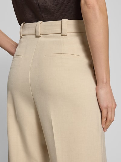Frauenmodel trägt Wide Fit Stoffhose mit Viskose-Anteil Modell 'Paris' von Mango, beigefarben, feine Bügelfalten, Detailaufnahme Rückansicht.