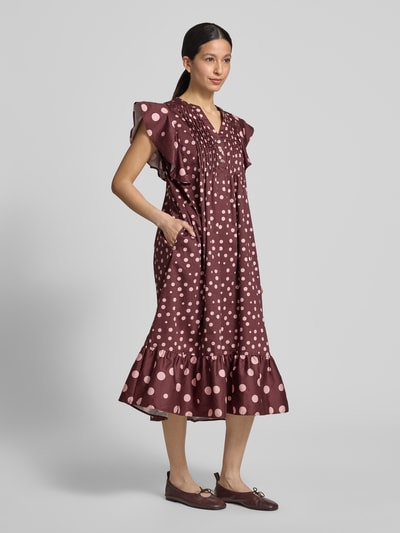 Frauenmodel trägt Relaxed Fit Midikleid mit gelegten Falten von Christian Berg Woman, braun mit rosa Punkten, reine Baumwolle, Ganzkörperansicht von vorne.