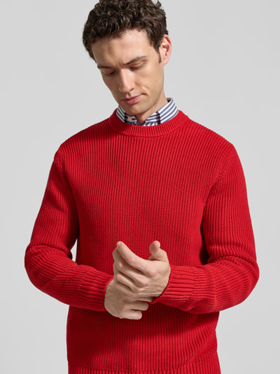 Männermodel trägt Regular Fit Strickpullover aus reiner Baumwolle von MCNEAL in Rot, sichtbare Struktur, Nahaufnahme Oberkörper.