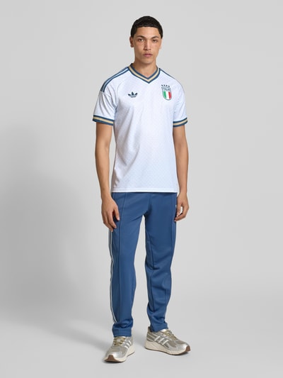 Männermodel trägt Italien Auswärtstrikot 2026 von adidas Sportswear, mehrfarbig, Regular Fit, V-Ausschnitt, Kurzarm, Ganzkörperansicht von vorne.