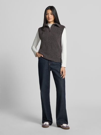 Kobiece modelka nosi bezrękawnik z mieszanki wełny z alpaką Model 'Thora' od MOS MOSH, krój slim fit, stójka, zamek błyskawiczny, długość tyłu w rozmiarze S: 64 cm, ciemnoszary, prosta tekstura, widok całej sylwetki z przodu.