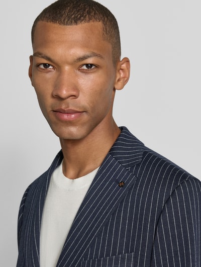 Männermodel trägt dunkelblaues Slim Fit Sakko mit weißen Streifen von Zuitable, Modell 'Nick', Nahaufnahme Oberkörper.